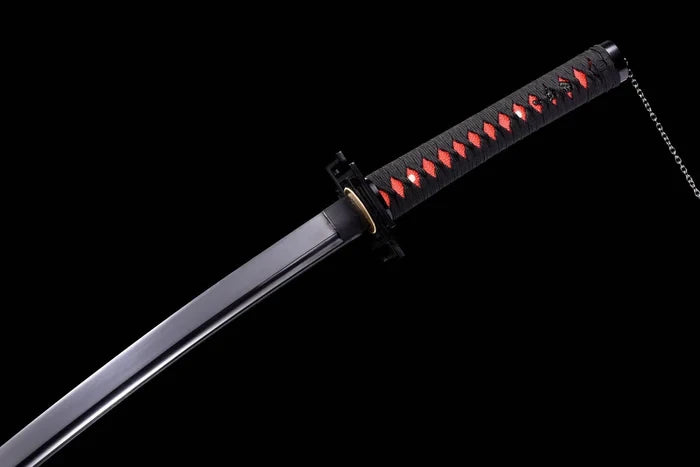 Close-up angle of a black custom samurai katana sword featuring a blacked-out blade, traditional black wrapped hilt over bright red ray skin, and a distinctive iron chain attached to the pommel against a black background.