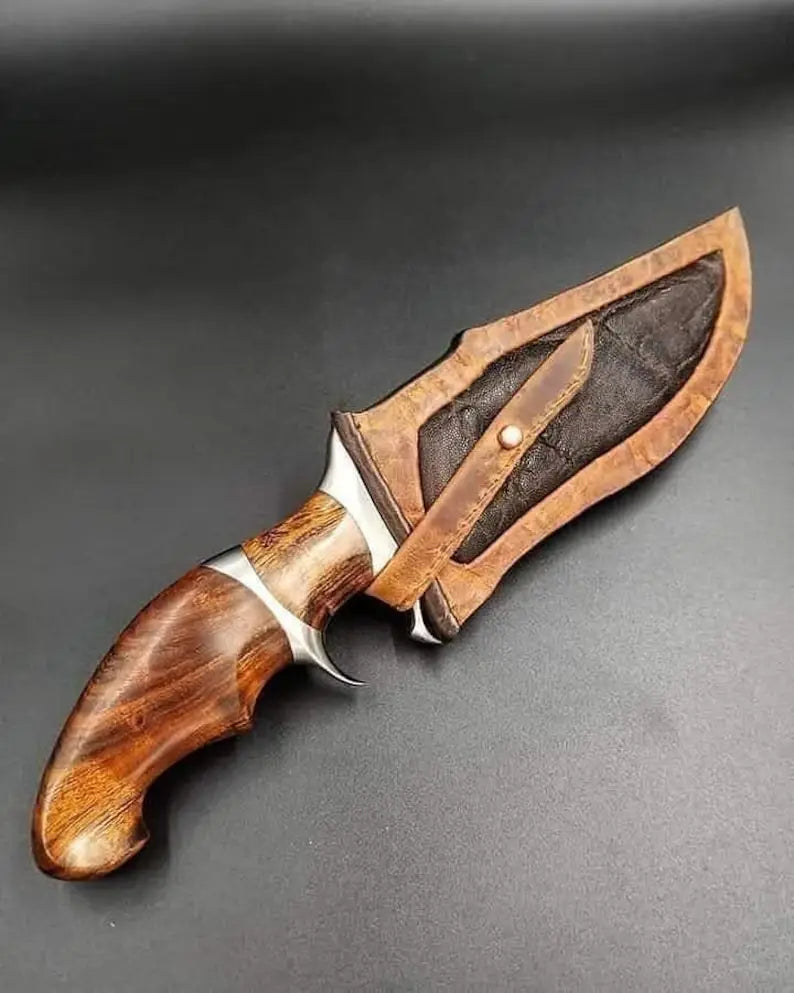 Close-up of a premium handmade knife showing the detailed exotic burl wood handle and high-quality stitched leather sheath.