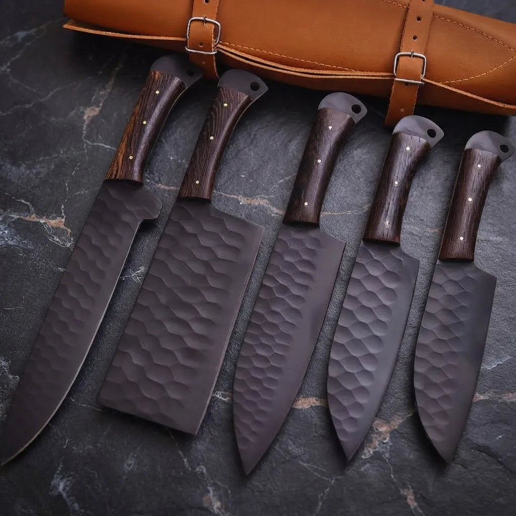 A 5-piece professional kitchen knife set featuring hammered carbon steel blades and dark hardwood handles, displayed with a premium leather storage roll on a dark stone background.