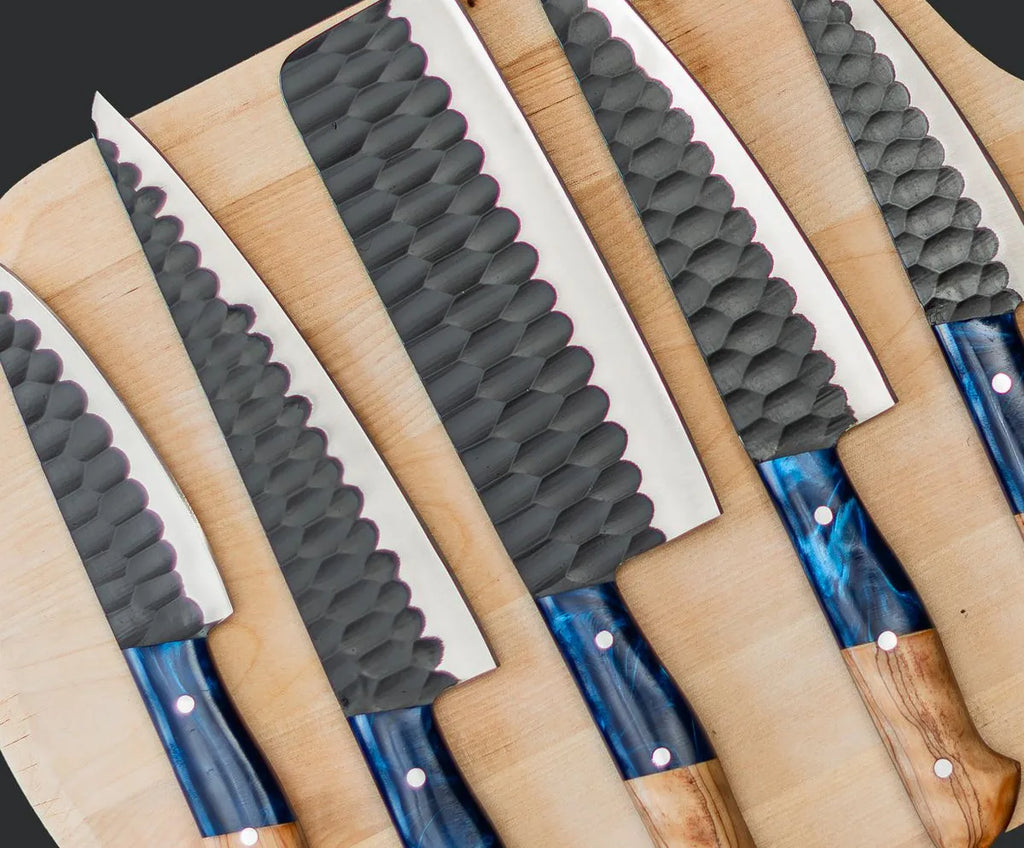 A professional 5-piece kitchen knife set featuring hammered finish blades and custom blue resin and natural wood handles, laid out on a wooden board.