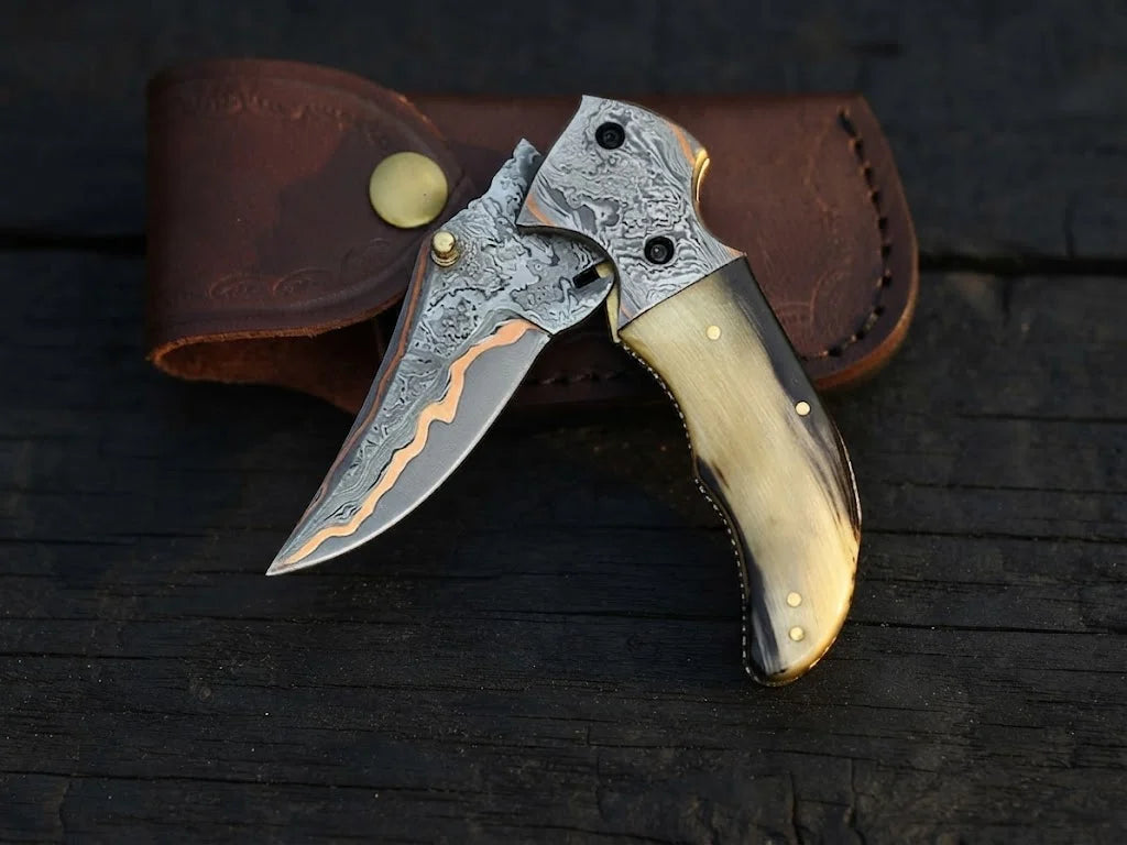 High-quality custom copper Damascus steel pocket knife showcasing vibrant copper layers and organic horn material alongside an artisan leather carry case for gift buyers