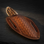 A professional handmade Western belt knife secured inside its hand-tooled leather pancake sheath, showcasing the genuine stag horn handle pommel on a dark stone background