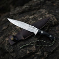 Custom-forged tactical Bowie knife showcasing a high-quality clip-point blade and durable leather carry sheath, ideal for knife collectors and survivalists.