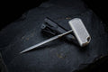 Premium handcrafted titanium push dagger with textured T-handle, minimalist EDC defense punch tool, displayed on a black stone background with its custom kydex sheath.