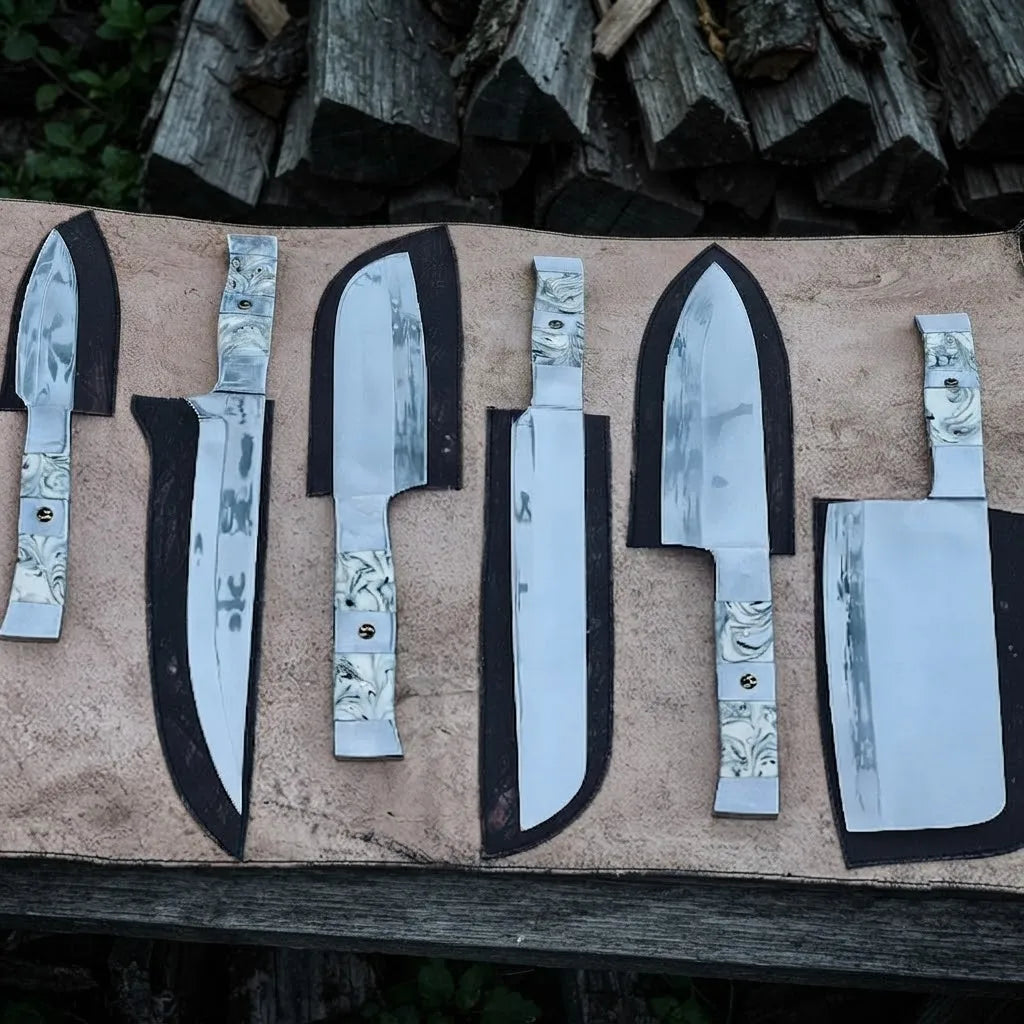 A set of premium hand-forged kitchen knives featuring elegant marble-patterned resin handles, displayed alongside custom-fitted leather sheaths on a rustic wooden surface.