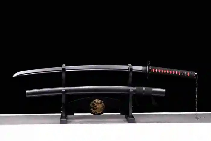 Handcrafted black Damascus steel katana sword displayed on a black wooden stand, featuring a blacked-out blade, red and black wrapped hilt, and matching textured scabbard.