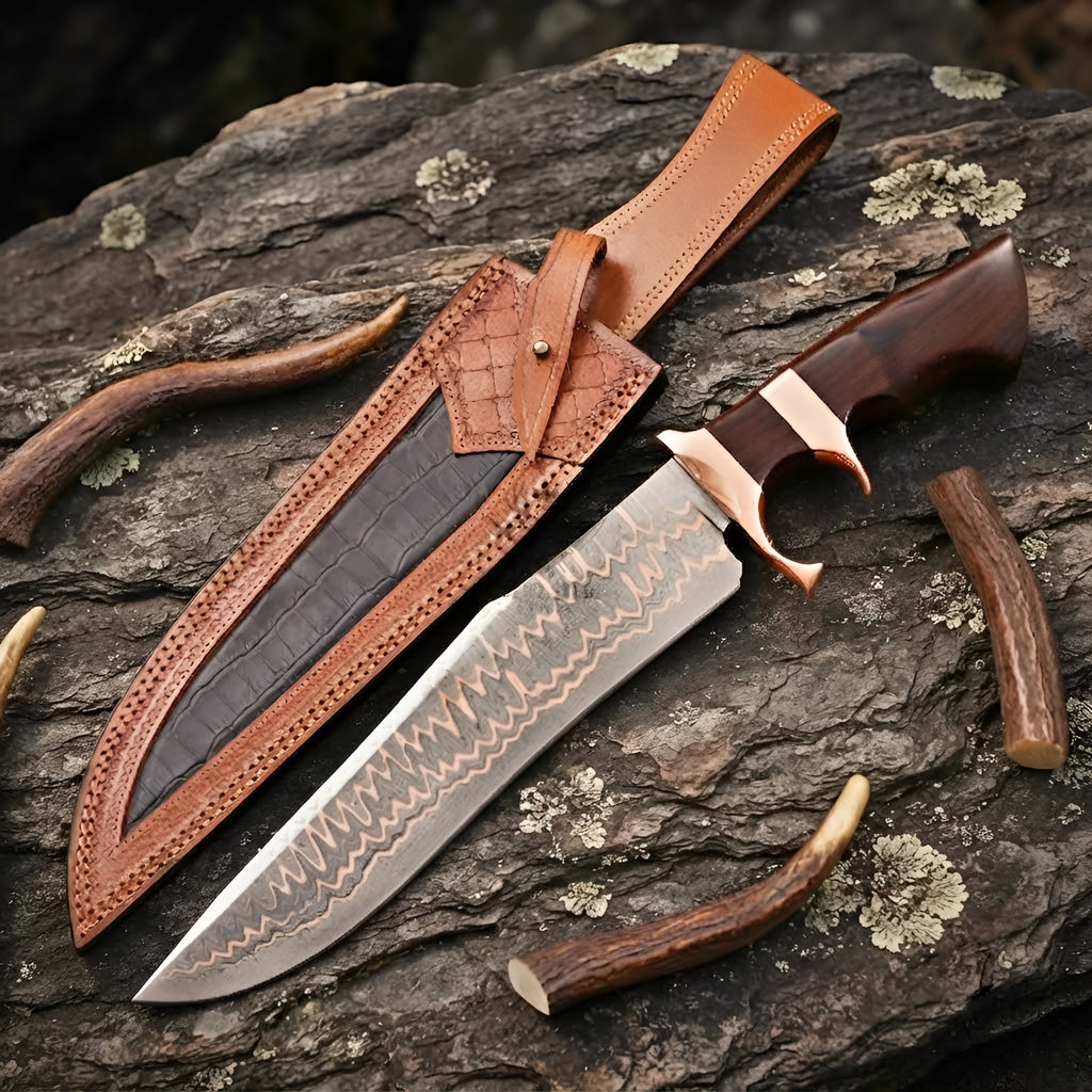 A professional handmade Copper Damascus Bowie knife featuring a double copper guard and rich wood handle, paired with a custom-tooled leather sheath on a textured stone surface
