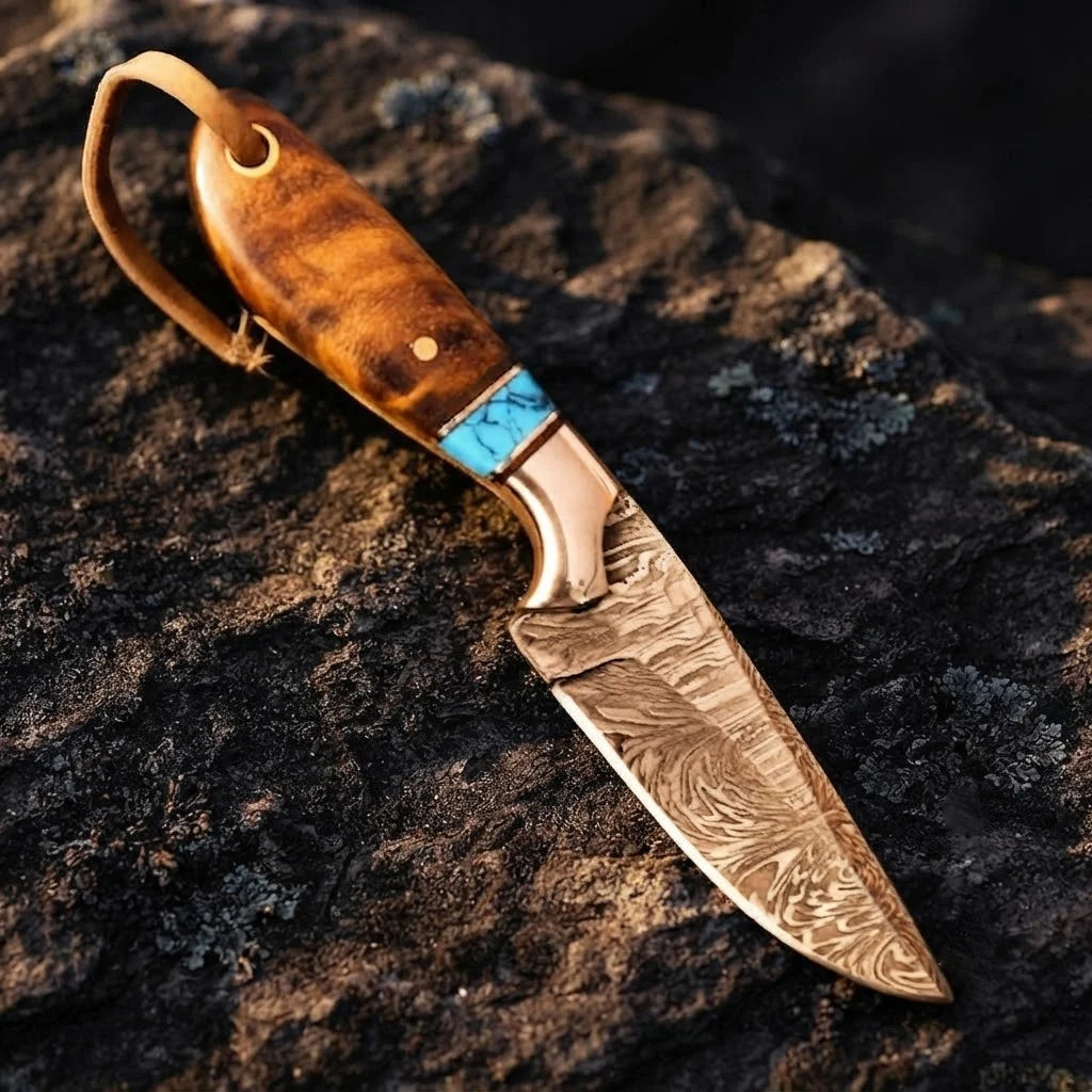 A professional handmade Damascus cowboy hunting knife displayed on a rugged stone surface, highlighting its rosewood handle, vibrant turquoise spacer, and custom-forged blade