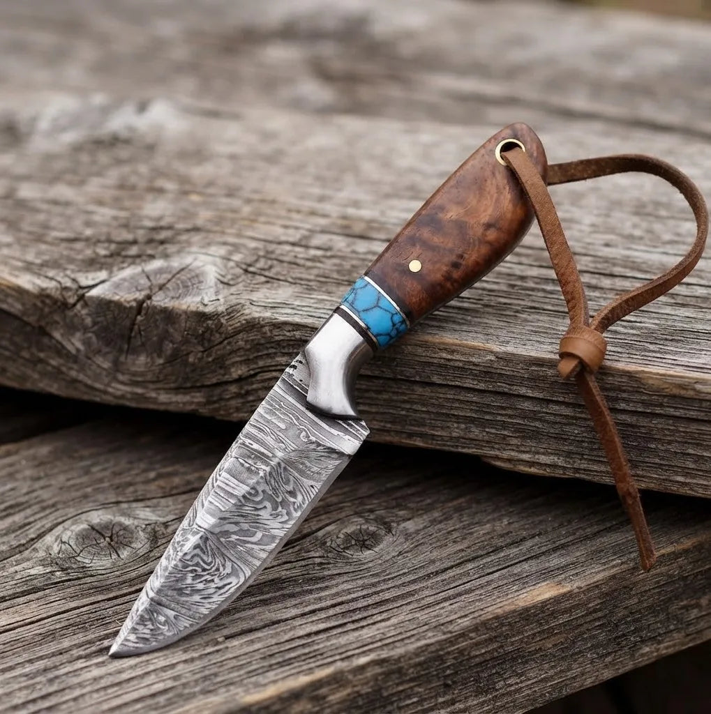 Handmade Damascus cowboy hunting knife featuring a premium rosewood handle with turquoise inlay, a fixed blade, and a leather lanyard, displayed on a rustic wooden surface