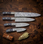 A professional 4-piece set of hand-forged Damascus steel kitchen knives featuring sleek, dark handles, arranged elegantly with cinnamon sticks, bay leaves, and spices on a dark wooden board.
