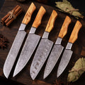 A professional 5-piece Damascus steel kitchen knife set featuring stunning natural olive wood handles, arranged elegantly with cinnamon and dried herbs.