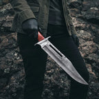 A professional handmade Rambo III style Bowie knife with a VG10 Damascus steel blade held in a gloved hand, showcasing its impressive size and tactical design