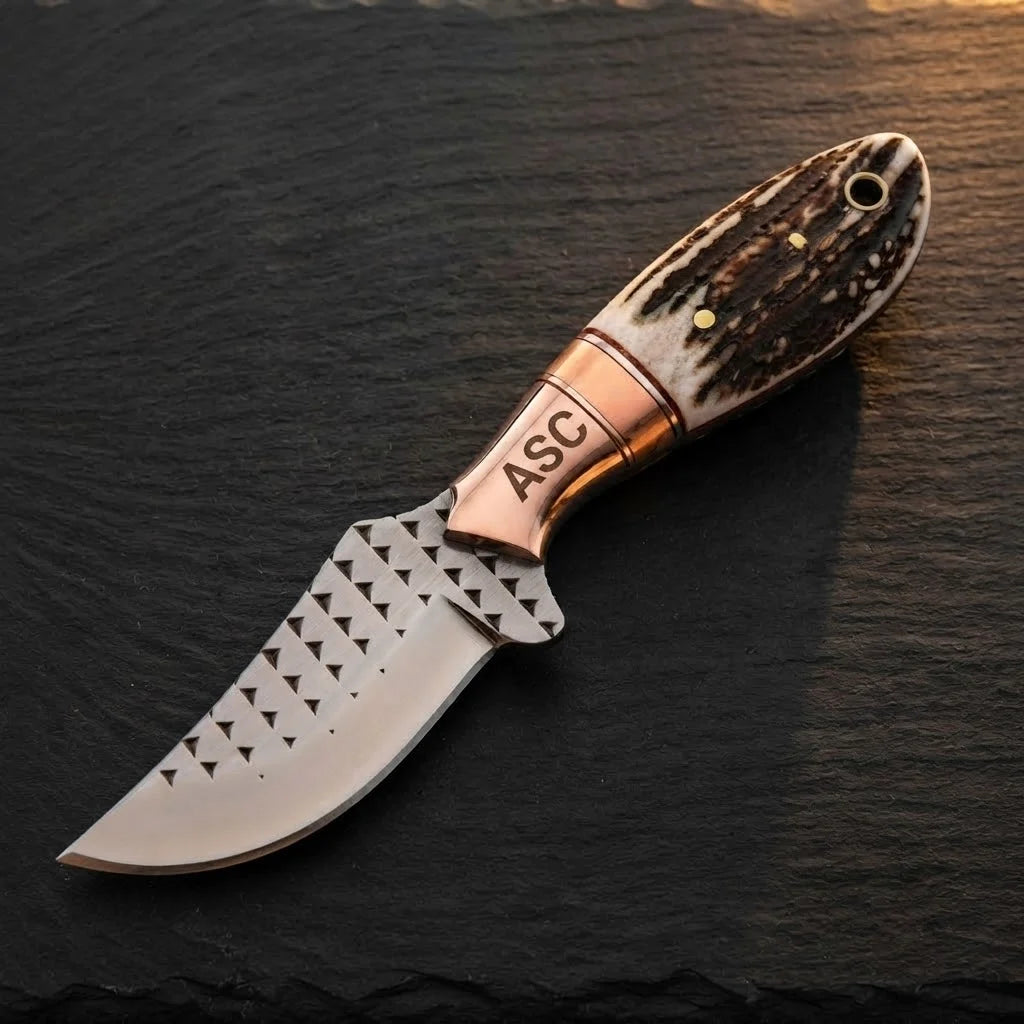 A professional top-down view of a handmade Western belt knife featuring a D2 rasp steel blade, engraved ASC copper bolster, and genuine stag horn handle on a dark stone surface