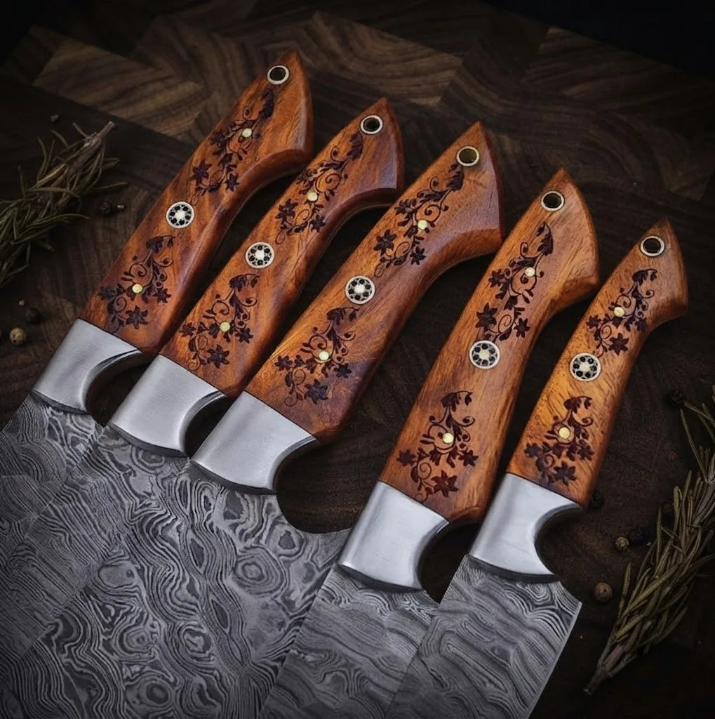 A set of luxury hand-forged Damascus steel kitchen knives featuring unique wavy blade patterns and intricate, hand-carved wooden handles, arranged with cinnamon and bay leaves