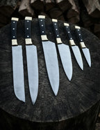 A professional 6-piece handcrafted kitchen knife set featuring classic black handles with brass bolsters, arranged on a rustic wooden log background.